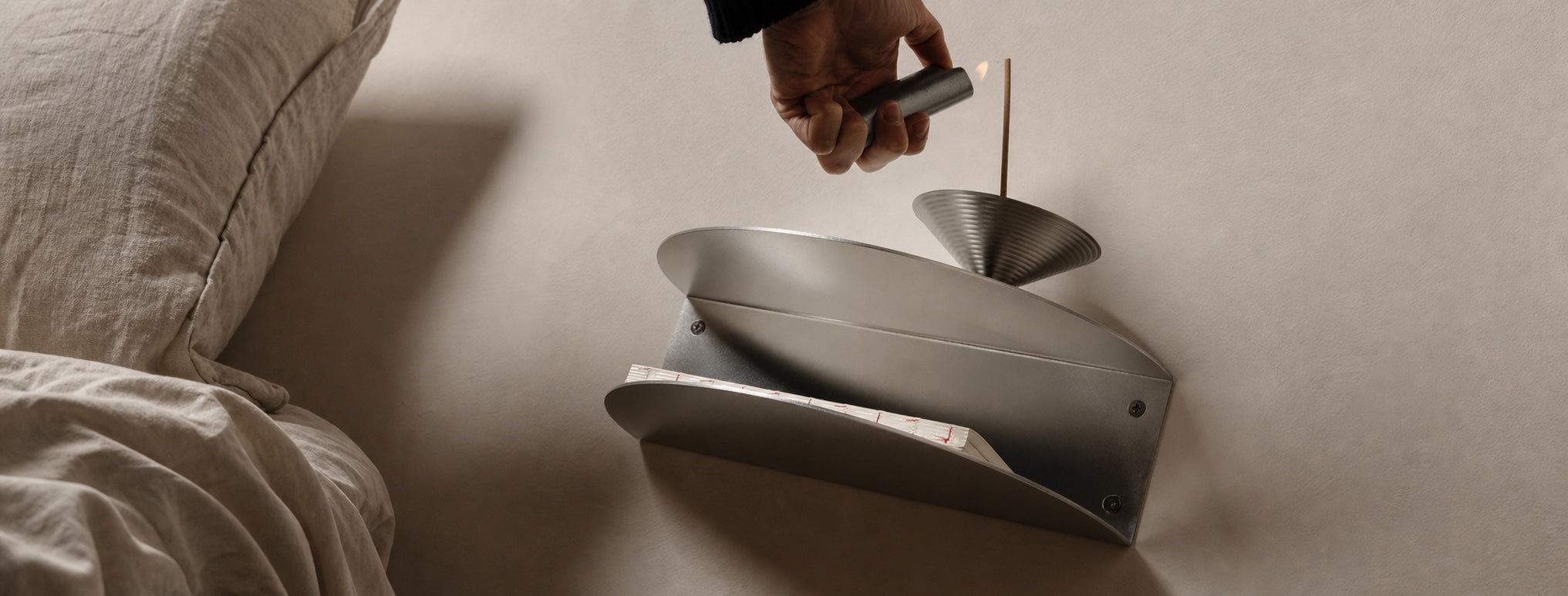 Lighting incense on a Made of Tomorrow anodised aluminium bedside shelf